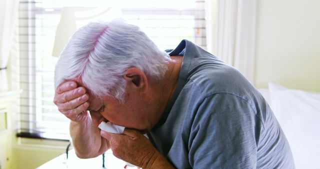 Sick senior man coughing in bedroom at home