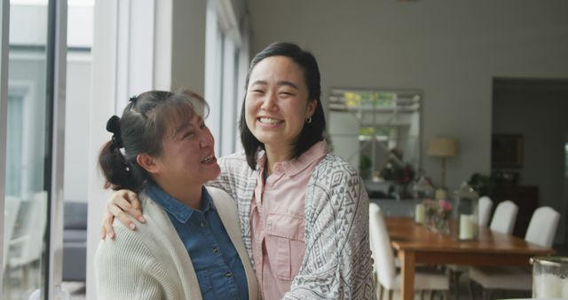 Portrait of happy asian mother and adult daughter embracing and smiling in dining room - Download Free Stock Photos Pikwizard.com
