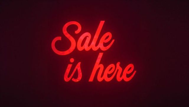 Glowing red neon script sale is here sign casting halo on dark textured wall
