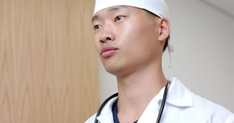Asian doctor wearing surgical cap and stethoscope portrait showing calm professional demeanor