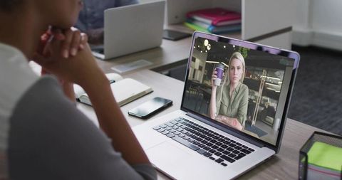 Person Watching Virtual Meeting on Laptop in Modern Office