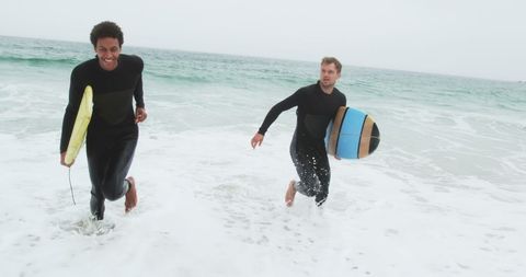Two Male Surfers Running on Beach with Surfboards