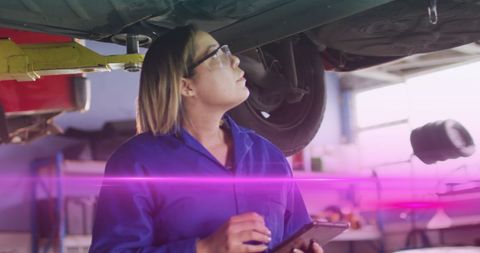 Female mechanic inspecting car with digital technology