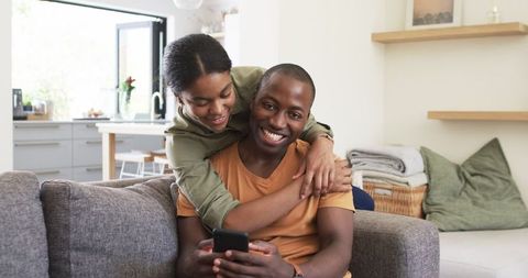 Happy Couple Cuddling on Couch with Smartphone