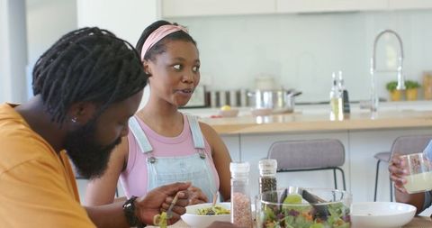 Family enjoying casual healthy salad and conversation at modern kitchen table