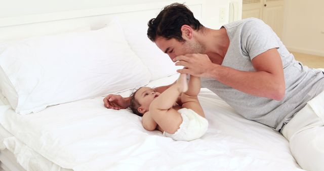 Handsome father playing with his baby on the bed