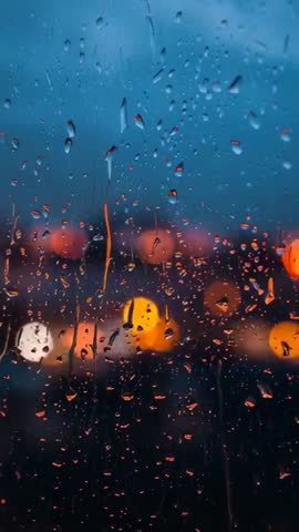 Raindrops sliding down glass panel with city bokeh lights at dusk cinematic vertical video