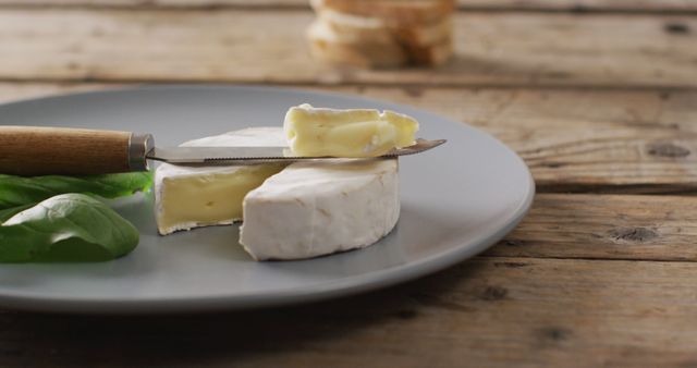 Creamy Brie Cheese on Plate with Knife and Basil Leaf - Download Free Stock Images Pikwizard.com