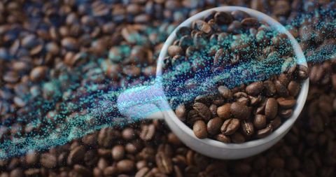 Roasted coffee beans in white ceramic cup with turquoise data stream overlay tech abstract