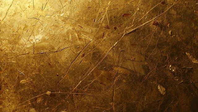 Textured golden metallic surface with vintage patina and scratches