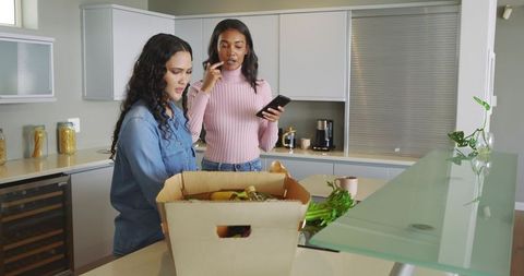 Two Friends Examining Home Delivery Produce in Modern Kitchen
