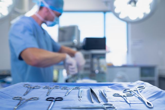 Surgical instruments arranged on table while surgeon performing operation in operating room at hospital