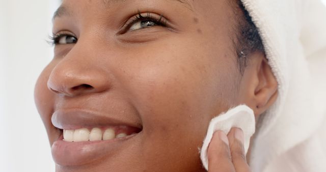 Smiling woman cleansing face with cotton pad - Download Free Stock Images Pikwizard.com