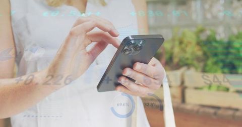 Mature woman tapping smartphone with fintech charts and graphs on outdoor patio