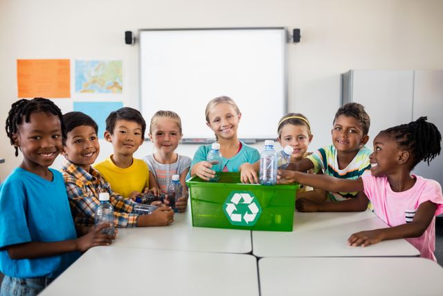 Diverse group of children smiling and recycling plastic bottles in a classroom. Ideal for educational materials, environmental campaigns, sustainability programs, and promoting teamwork and eco-friendly practices among young students.