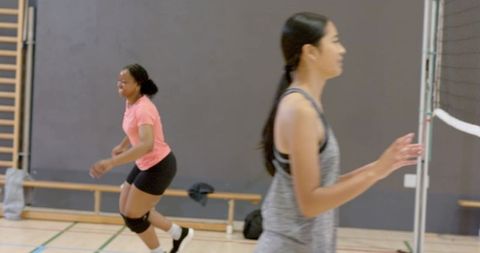 Diverse female teammates practicing indoor volleyball showing teamwork and athletic movement