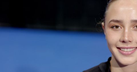 Smiling woman in black sportswear on blue tennis court with copy space