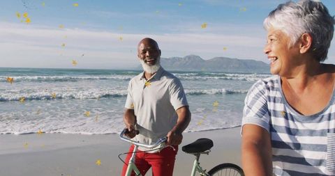Joyful couple with bicycles on seaside adventure amidst confetti