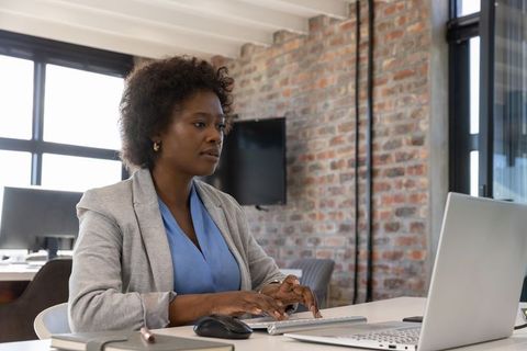 African American Female Professional Using Laptop in Modern Workspace
