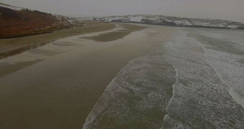Tranquil winter coastline and ocean waves meeting sandy shore