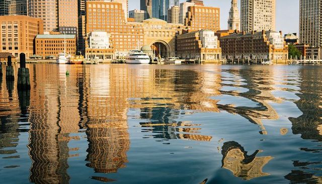 Harbor skyline reflecting on rippling water with arched waterfront building and clock tower