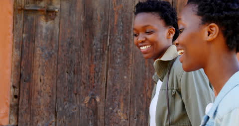 Smiling Twin Sisters Walking Together in Urban Environment