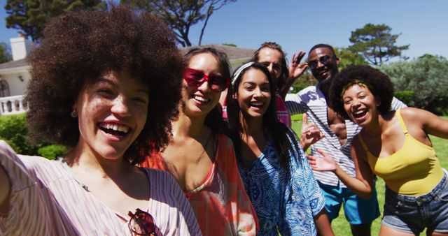 Portrait of diverse group of friends looking at camera and smiling at a pool party. Hanging out and relaxing outdoors in summer.