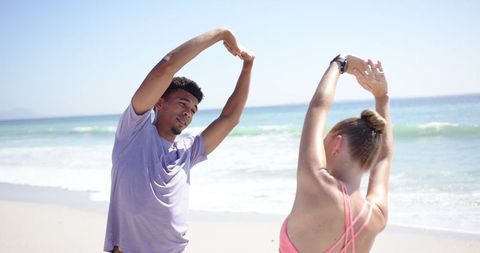 Dynamic Beach Workout with Multiracial Duo Enjoying Outdoor Fitness