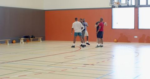 Basketball players huddling on indoor gym court practicing teamwork and strategy