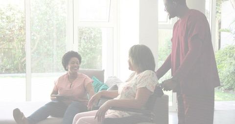 Family chatting and assisting older woman in wheelchair in bright living room