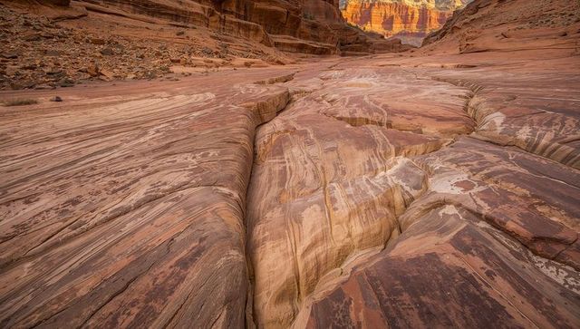 Sunlit striated sandstone gorge leading through flowing layers and desert erosion