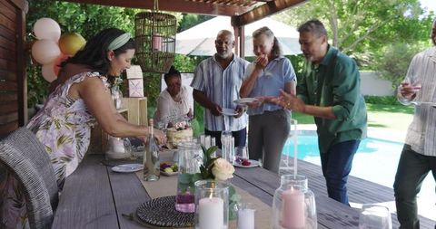 Seniors celebrating with cake and drinks by poolside in summertime