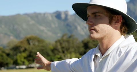 Cricket umpire signaling wide ball during sunny day match