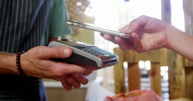 Close-up scene depicts customer making contactless payment with smartphone at market stall. Suitable for illustrating modern transaction methods, mobile technology advancements, business solutions, and convenience in shopping. Useful for articles, blog posts, advertising for fintech, mobile payment companies, and retail tech solutions.