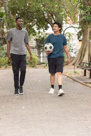 African american friends walking park carrying soccer ball casual urban sports lifestyle