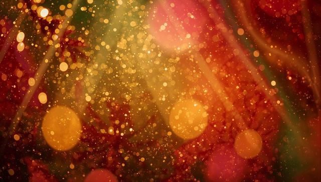 Shimmering golden and red bokeh backdrop with sparkling glitter and warm glow