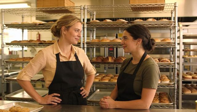 Two Female Bakers Collaborating Behind Counter in Busy Artisan Bakery Production Kitchen