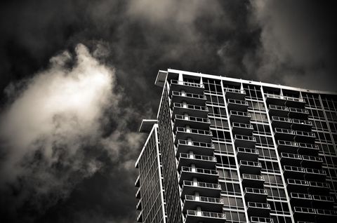 Modern high-rise condo building against dramatic cloudy sky