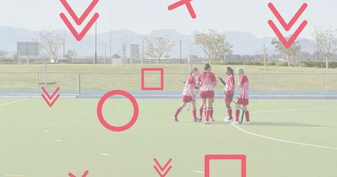 Field hockey team huddling on green turf wearing red striped jerseys and red socks