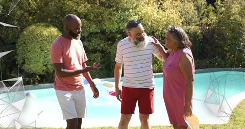 Three friends chatting poolside in sunlit backyard during casual summer gathering