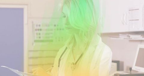 Female clinician reviewing patient chart in exam room with stethoscope and monitor