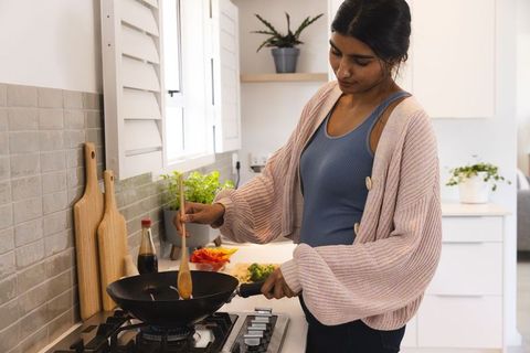 Young woman cooking healthy meal in modern kitchen