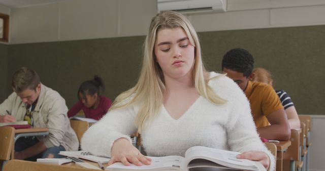 Young female student deeply engaged in studying in a classroom setting, ideal for highlighting scenes of education, academic concentration, student life, and learning environments.