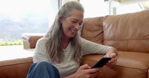 Smiling Woman Relaxing at Home Browsing Smartphone