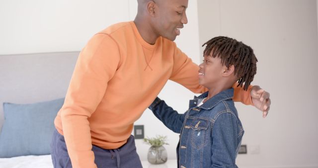 Joyful African American father and son embracing and sharing a moment at home. Great for themes around family bonding, parenting, and happy moments between loved ones. Ideal for use in advertisements, websites, and social media content related to family life, relationships, and fatherhood.