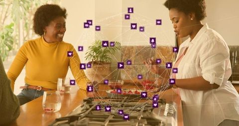Two women cooking with augmented reality social network overlay in modern kitchen