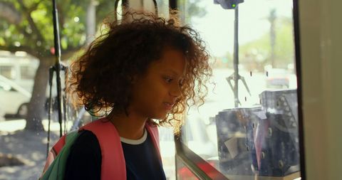 Curly-Haired Girl Traveling on Sunlit Bus with Enthusiasm
