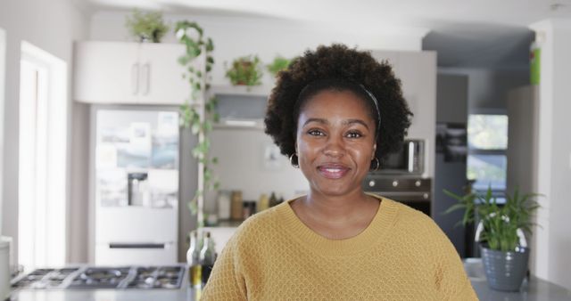 Portrait of happy african american woman with black hair smiling in kitchen at home, copy space. Lifestyle and domestic life, unaltered.