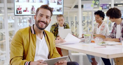 Smiling businessman in modern office setting with team collaborating
