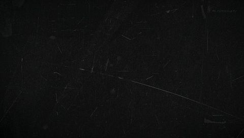 Worn black grunge backdrop featuring diagonal scratch, fine scuffs, dust specks